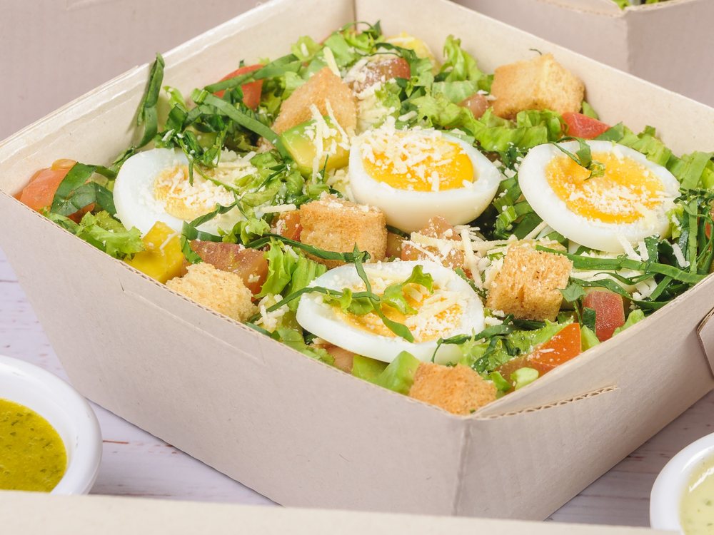Ensalada César con huevo, tomate, parmesano y crotones sobre lechugas frescas